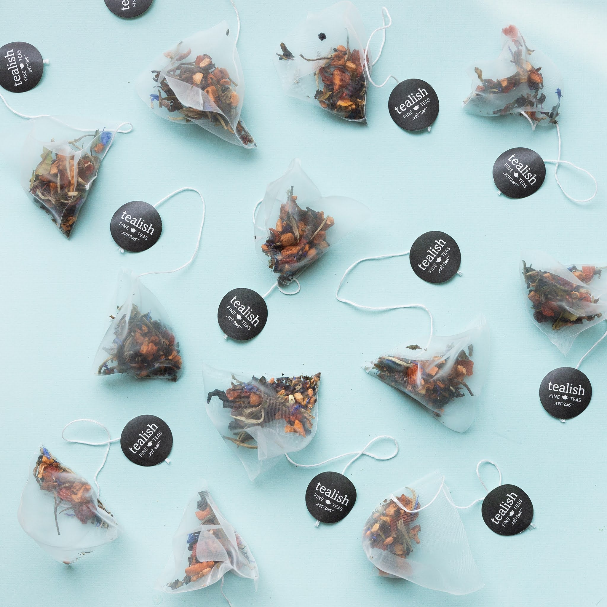 a picture of multiple turmeric lime green tea bags spread around in a sky blue background