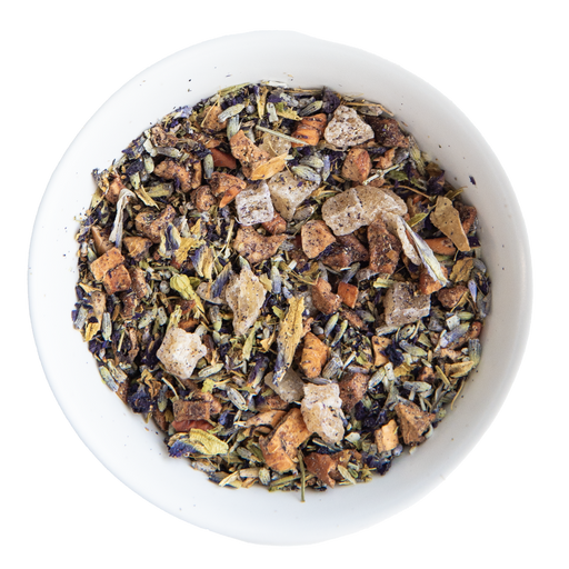 Assorted dried herbs and teas in a white bowl on a white background