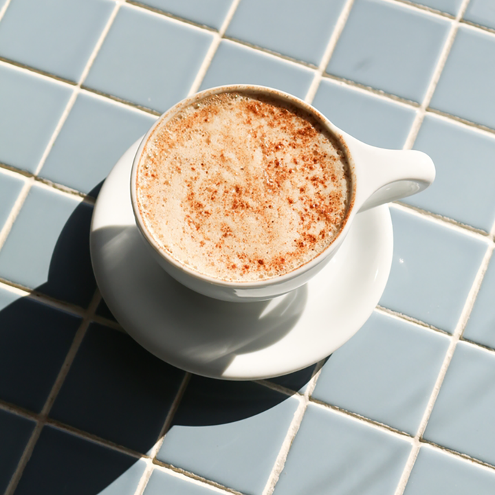 A cup of tea with a creamy top sprinkled with spices, possibly representing a latte made from the &