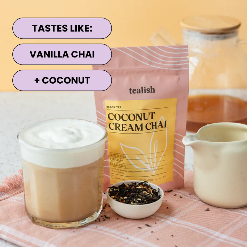 A stand-up pouch of tealish Coconut Cream Chai tea is shown on a pink plaid cloth beside a glass of iced coffee with foam, a small bowl of loose tea, and a cream pitcher. Text on the image reads 'TASTES LIKE: VANILLA CHAI + COCONUT'.