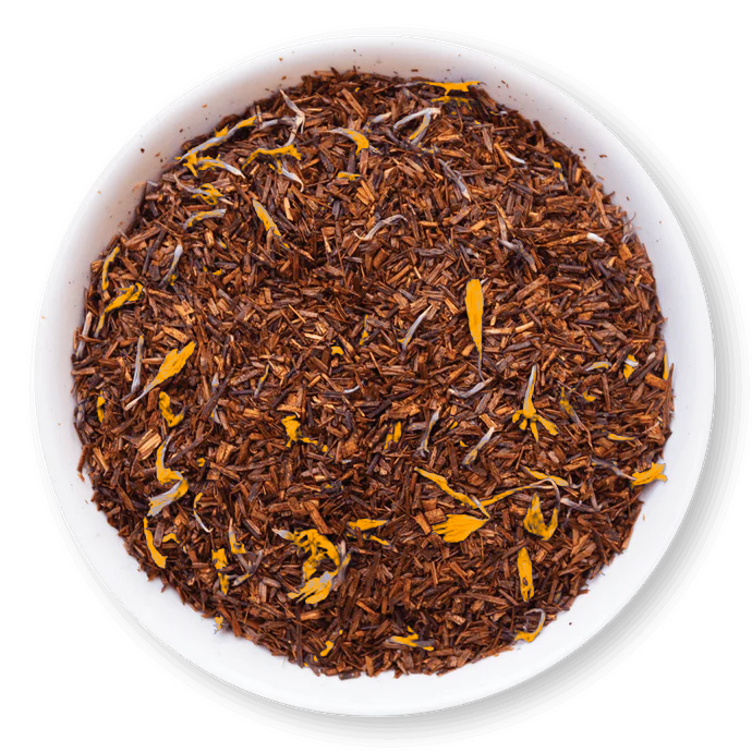 Close-up of rooibos tea leaves with orange pieces in a white bowl on a white background