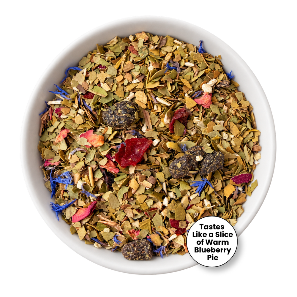 A top-down view of a white bowl filled with loose-leaf herbal tea blend. The tea contains dried green leaves, pink and red flower petals, blue blossoms, and dark brown tea leaves.