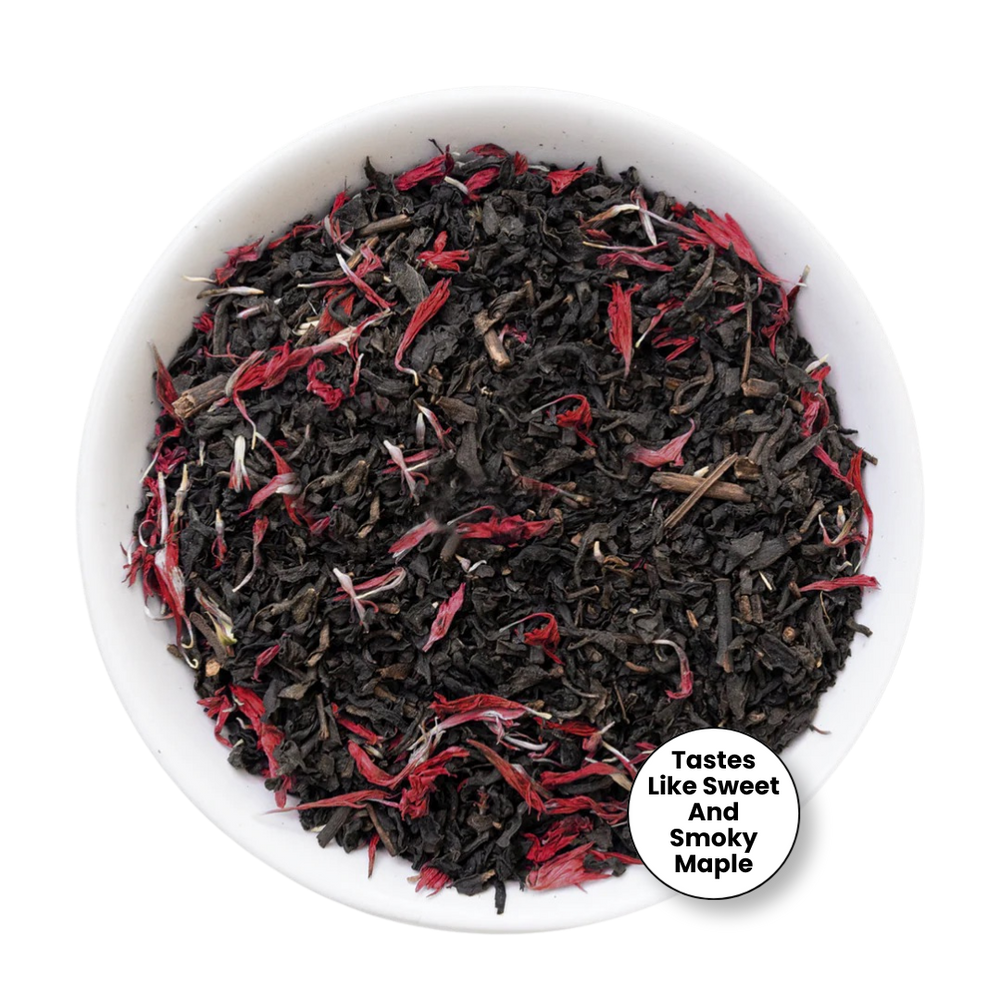 A top-down view of loose-leaf tea inside a white bowl, featuring dark black tea leaves mixed with bright red dried flower petals. A circular badge in the bottom right corner reads 'Tastes Like Sweet And Smokey Maple'.