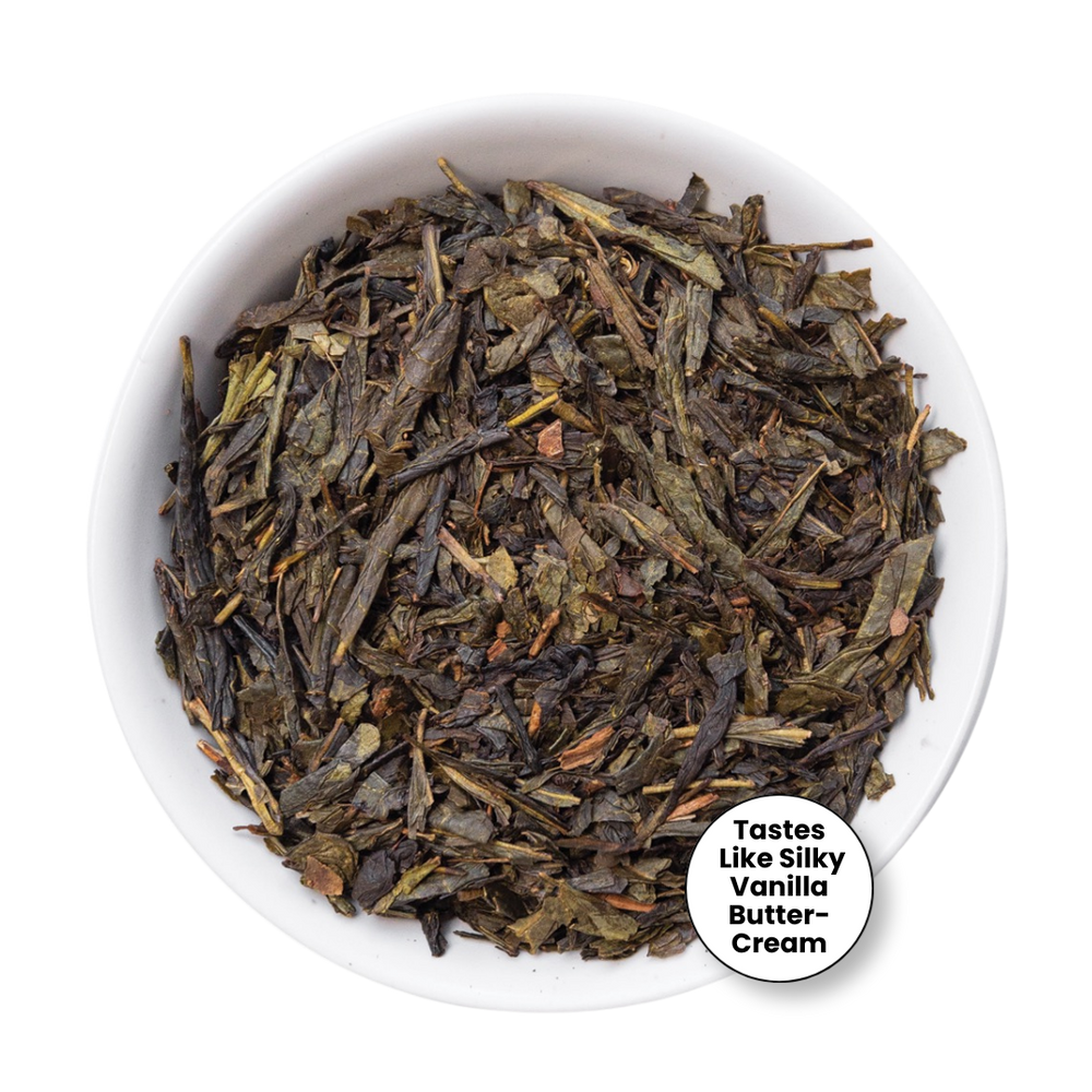 Loose leaf tea leaves in a small white bowl, with a circular label that reads 'Tastes Like Silky Vanilla Butter-Cream' on a white background.