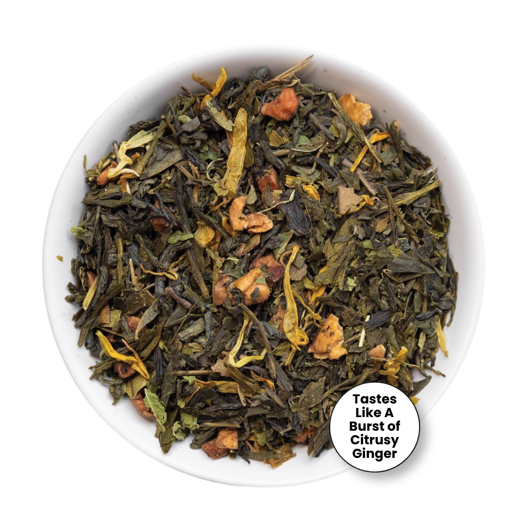 A top-down view of loose-leaf herbal tea in a white bowl, featuring dark green tea leaves mixed with dried citrus peel, ginger, and yellow botanical pieces. A white circular badge in the bottom right corner reads, &