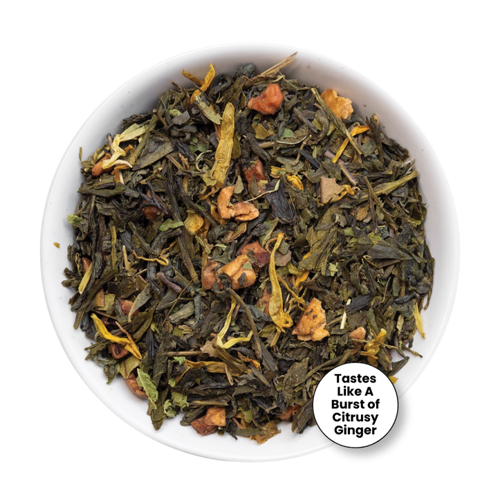 A top-down view of loose-leaf herbal tea in a white bowl, featuring dark green tea leaves mixed with dried citrus peel, ginger, and yellow botanical pieces. A white circular badge in the bottom right corner reads, &