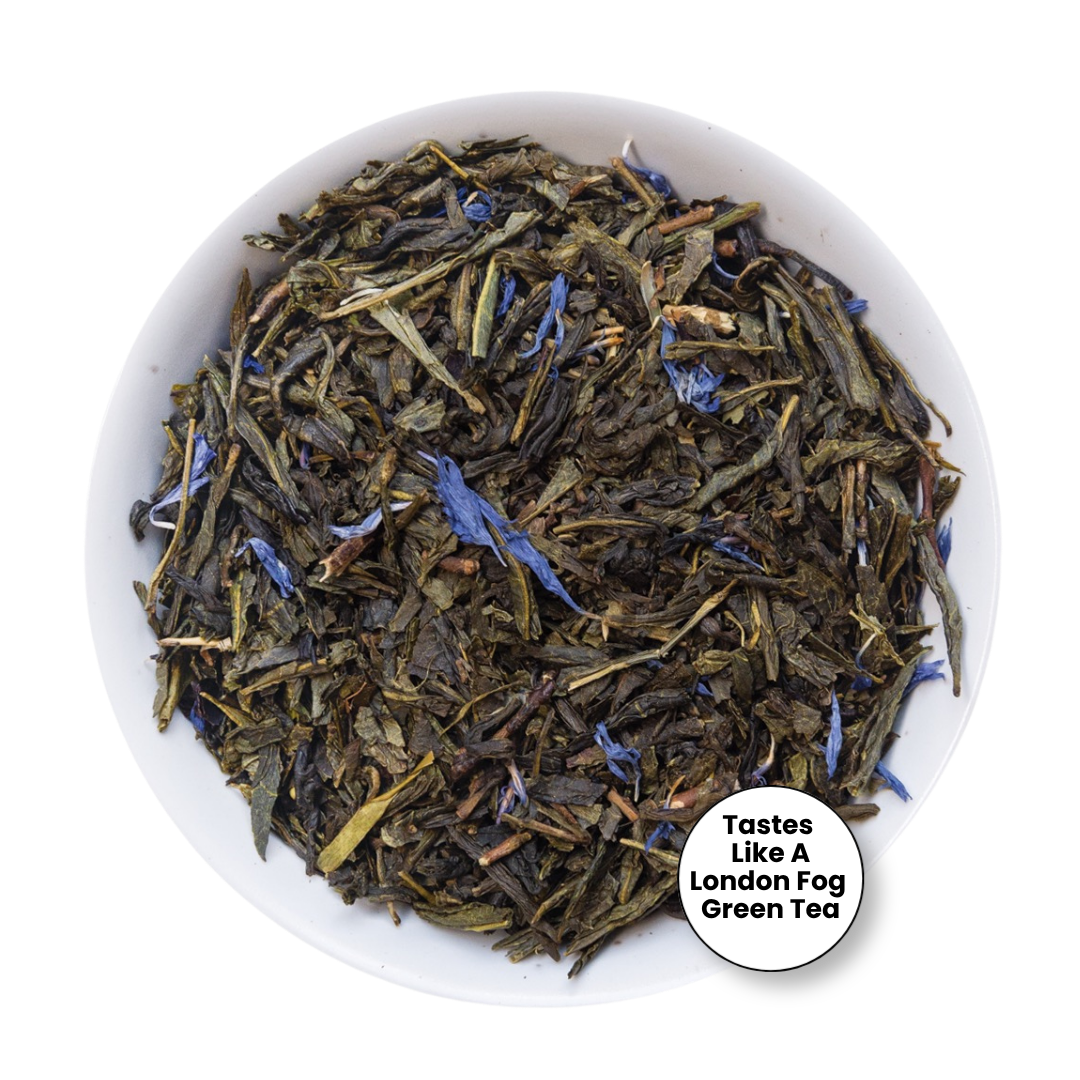 Loose leaf tea in a white bowl, featuring dark green and brown leaves with small blue flower accents. A white circular badge in the bottom right corner reads &