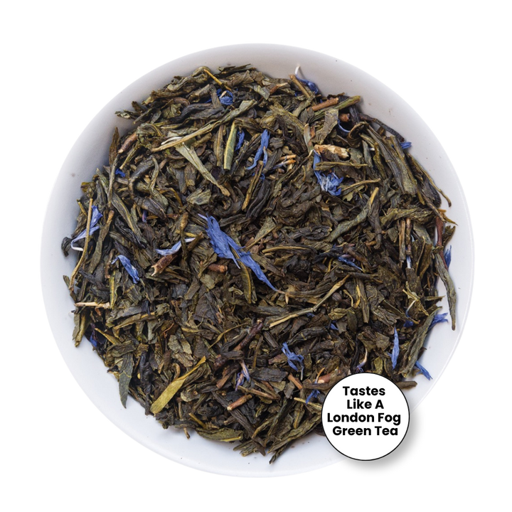 Loose leaf tea in a white bowl, featuring dark green and brown leaves with small blue flower accents. A white circular badge in the bottom right corner reads &