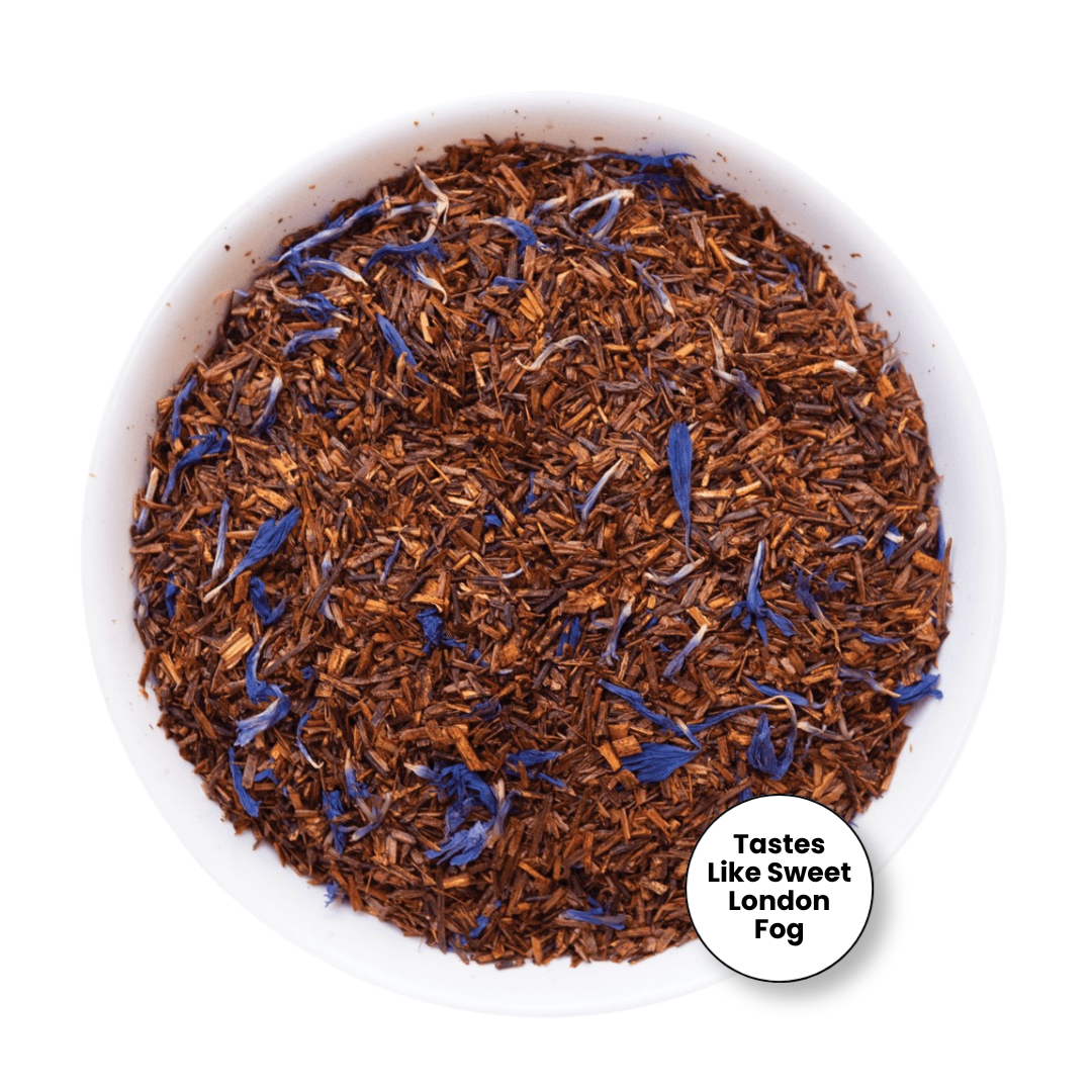 A top-down view of loose-leaf tea in a white bowl, featuring brown tea leaves mixed with blue flower petals. A small white circular badge in the bottom right corner reads &