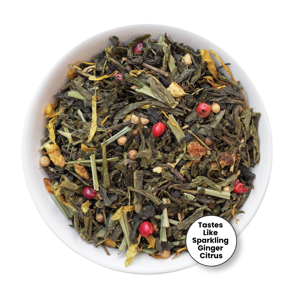 A top-down view of a white bowl filled with loose-leaf herbal tea blend, featuring dried green leaves, yellow citrus peel, small brown pieces, and bright red berries. A circular badge in the lower right corner reads 'Tastes Like Sparkling Ginger Citrus'.