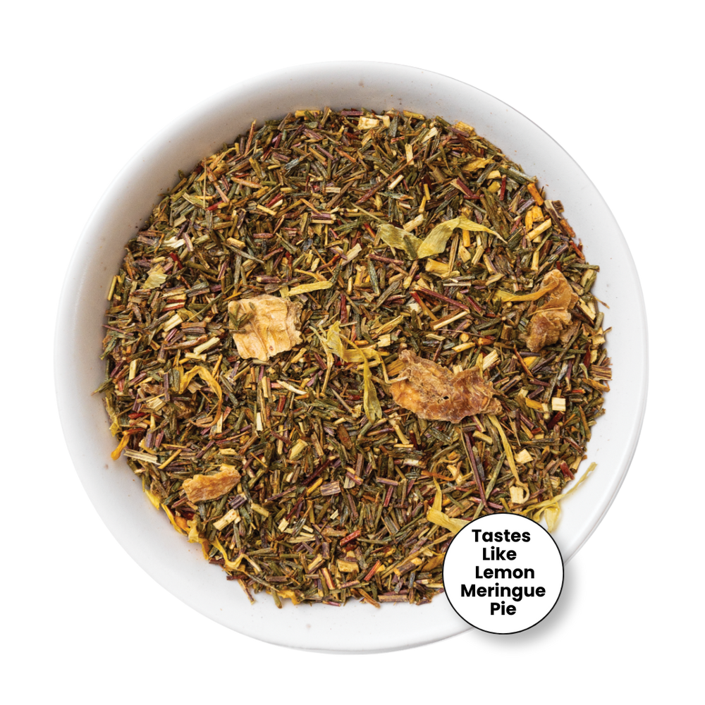 A top-down view of a loose leaf herbal tea blend in a white bowl, with a small circular badge in the lower right that reads 'Tastes Like Lemon Meringue Pie.' The tea contains mixed dried herbs, citrus pieces, and light brown chunks.