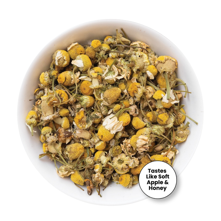 Dried chamomile tea loose leaves in a white bowl, with a circular badge in the bottom right corner that reads &