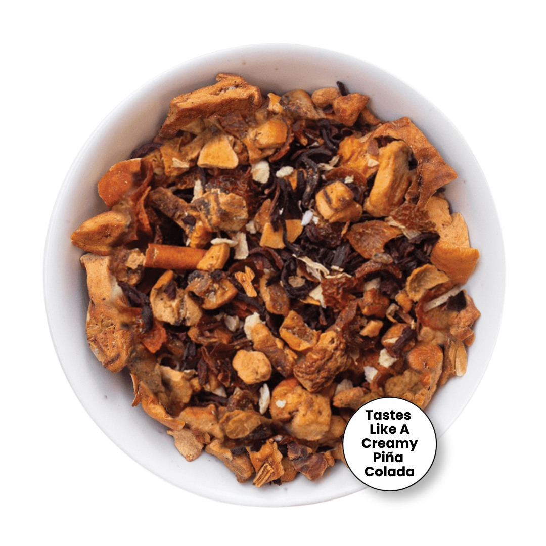 A top-down view of a white bowl filled with a textured, chunky snack mixture made of golden-brown pieces, dark brown bits, and small white flakes. A white circular badge in the bottom right corner reads &