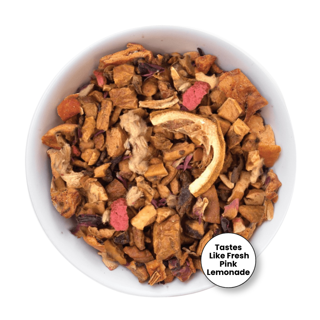 A top-down view of a white bowl filled with dried fruit and vegetable pieces for pet chews, including orange slices, pink dried pieces, and brown root vegetables. A circular badge in the bottom right corner reads &
