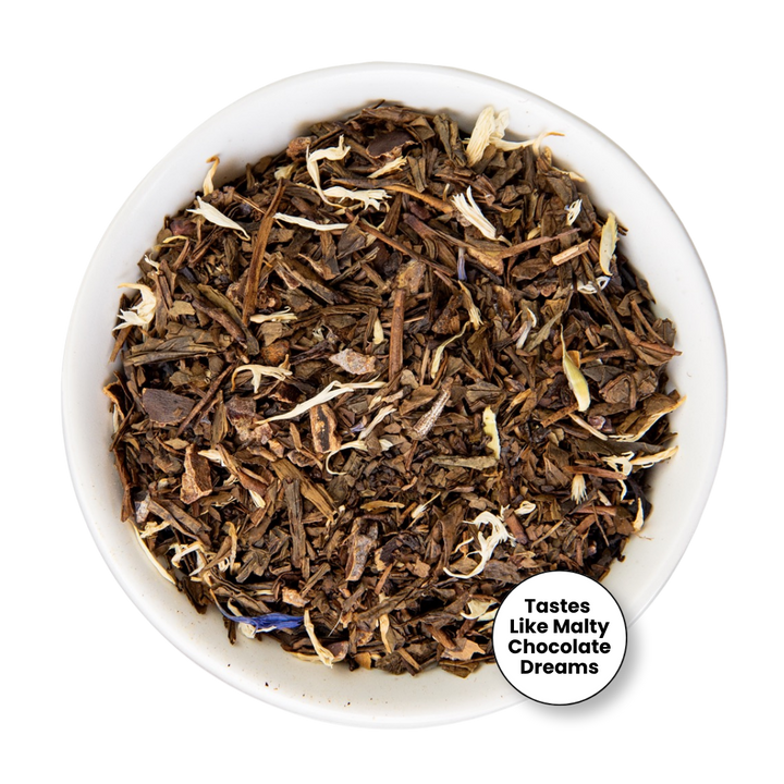 Loose leaf tea blend in a white bowl, featuring dark brown and medium brown pieces with small white flower petals and a hint of blue, with a circular badge reading &