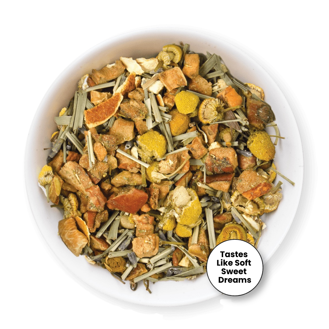 A top-down view of a white bowl filled with a loose herbal tea blend. The tea contains dried orange slices, yellow flower petals, green stems, and brown roots.