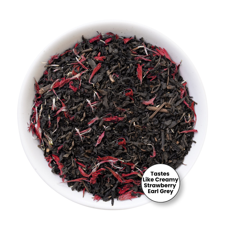 A top-down view of loose-leaf tea inside a white bowl, featuring dark black tea leaves mixed with bright red flower petals. A circular badge in the bottom right corner reads &