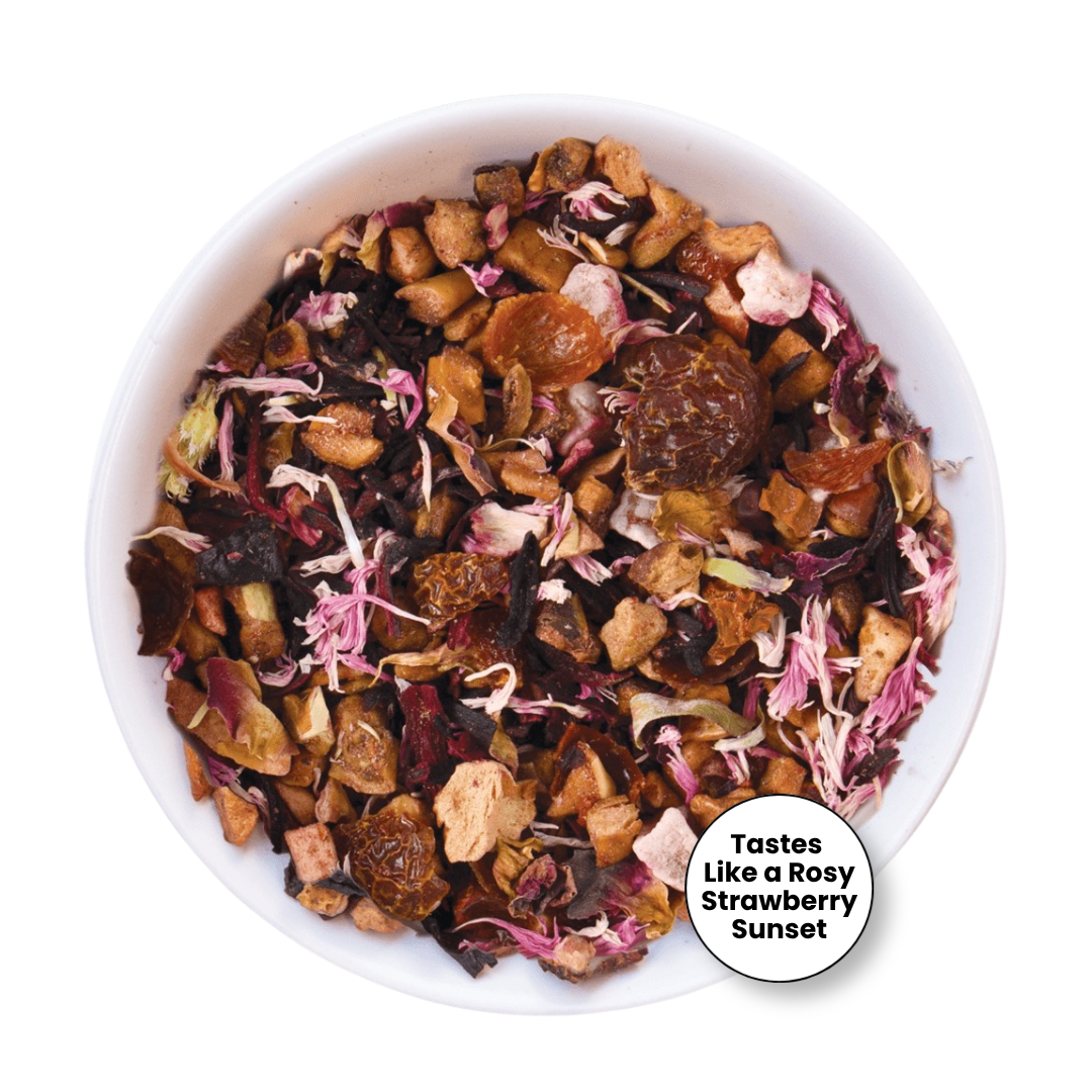 A top-down view of a white bowl filled with loose-leaf herbal tea blend, featuring dried flowers, fruit pieces, and tea leaves. A circular badge in the lower right reads &