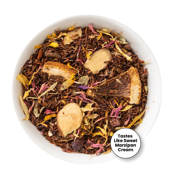 A top-down view of loose-leaf herbal tea in a white bowl, featuring dark brown tea leaves mixed with dried flowers in pink, yellow, and purple, and several light tan dried fruit slices. A white circular badge in the bottom right corner reads &