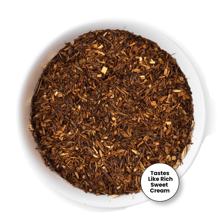 A top-down view of loose-leaf tea in a white bowl, with a small circular badge in the lower right that reads &