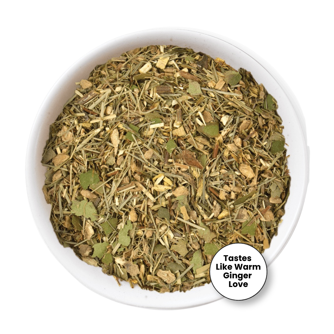 A top-down view of a white bowl filled with a loose herbal tea blend. The blend contains dried green leaves, light brown roots, and stems.