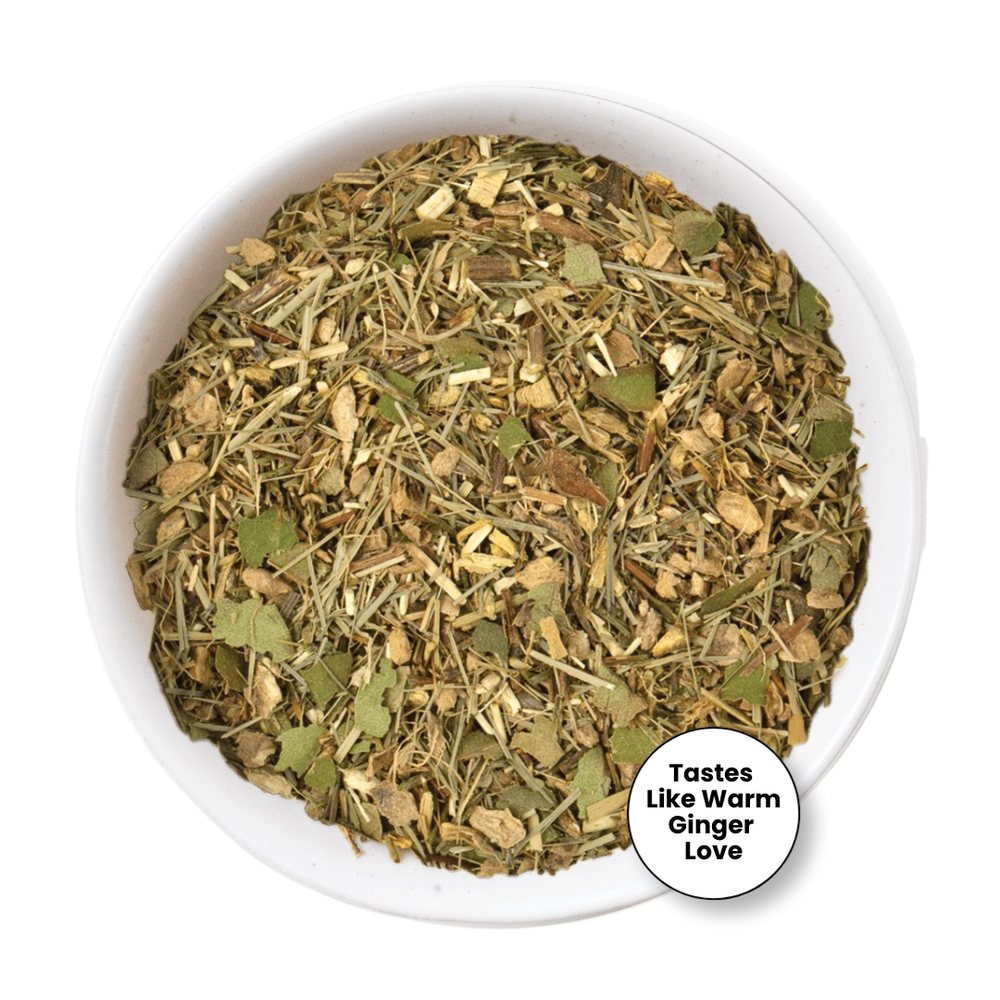 A top-down view of a white bowl filled with a loose herbal tea blend. The blend contains dried green leaves, light brown roots, and stems.