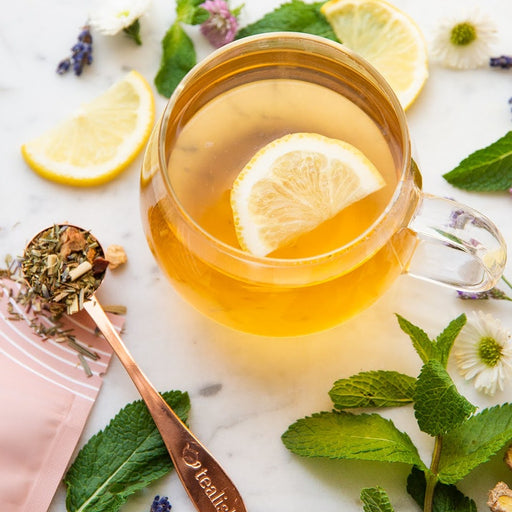 A cup of herbal tea with lemon slices and herbs around it, representing a relaxation tea routine.