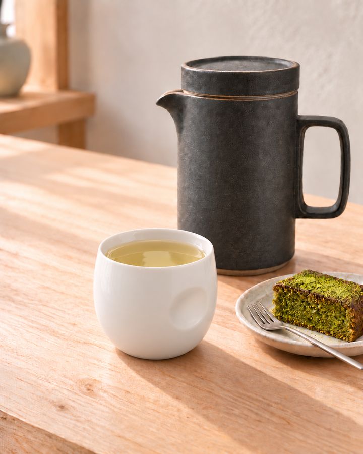 sencha green tea in white cup next to japanese matcha cake