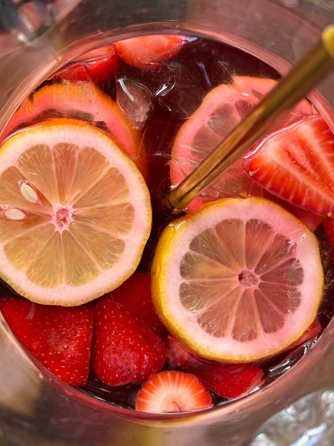 Punch bowl with sliced lemons, strawberries, and ice cubes.