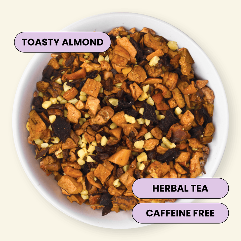 A top-down view of a white bowl filled with loose herbal tea blend labeled 'TOASTY ALMOND,' with additional text badges reading 'HERBAL TEA' and 'CAFFEINE FREE' on a light cream background.