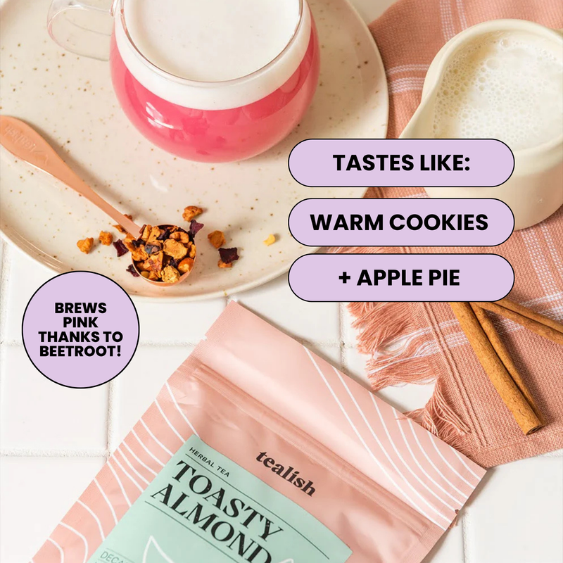 A styled flat-lay featuring a pouch of tealish Toasty Almond Herbal Tea in the background, with a pink drink on a saucer, a small bowl, cinnamon sticks, and text callouts describing flavor notes.