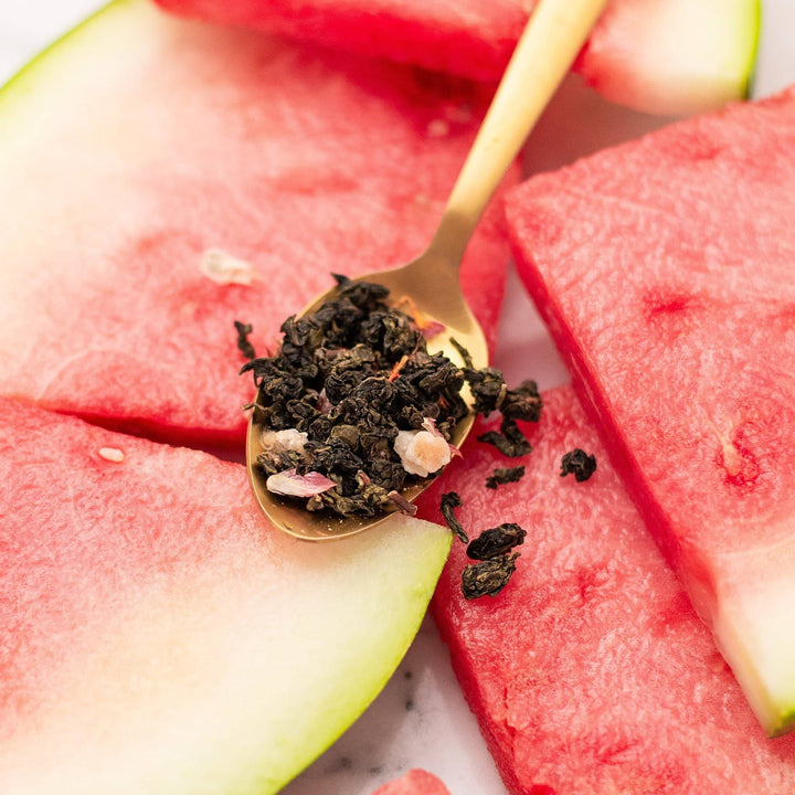a picture of watermelon oolong loose leaf tea in a spoon with watermelons in the background